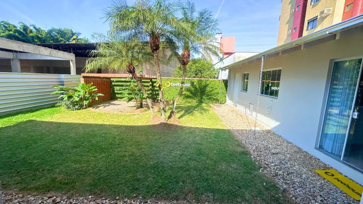 Jardim da sede da Beehouse, com gramado e acesso ao espaço interno.