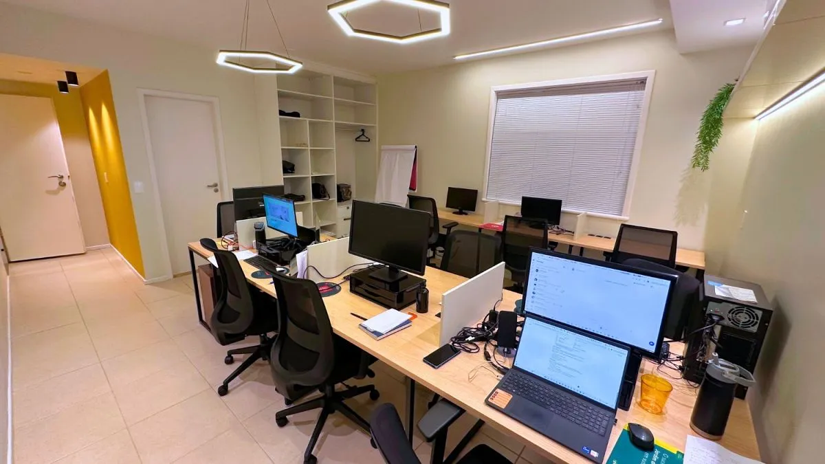 Ambiente de trabalho da Beehouse, com mesas e computadores.